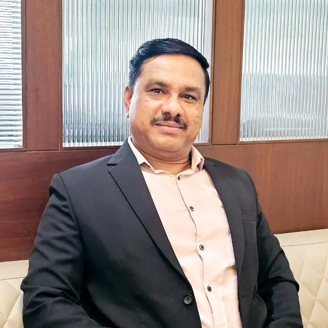 Abhishek Barve, smiling in a black blazer and pink shirt
