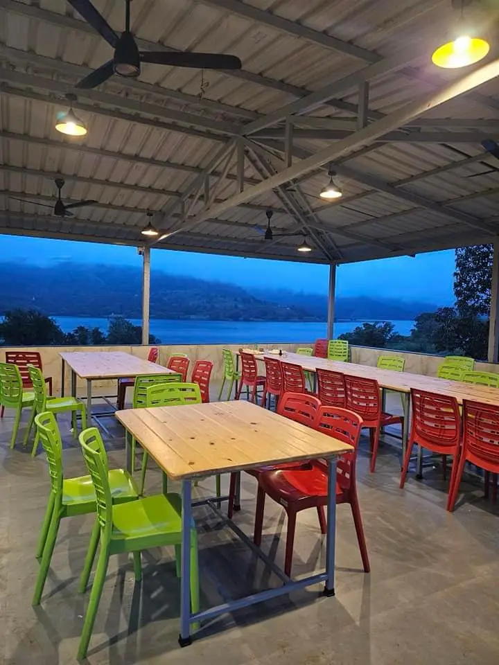 Outdoor seating area with colorful chairs and scenic lake view at dusk.