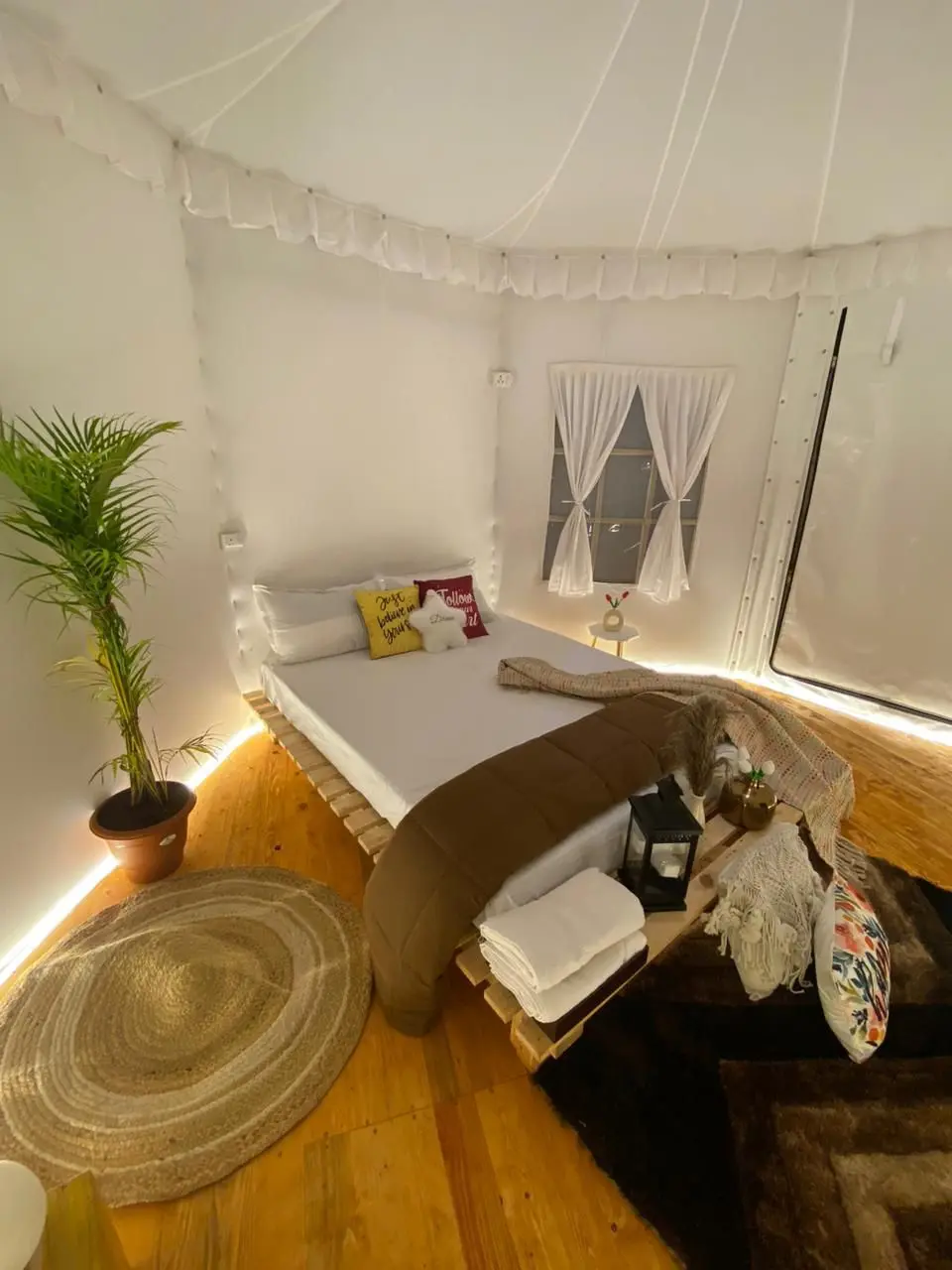 Cozy, minimalist bedroom with white walls, wooden floor, and soft lighting.